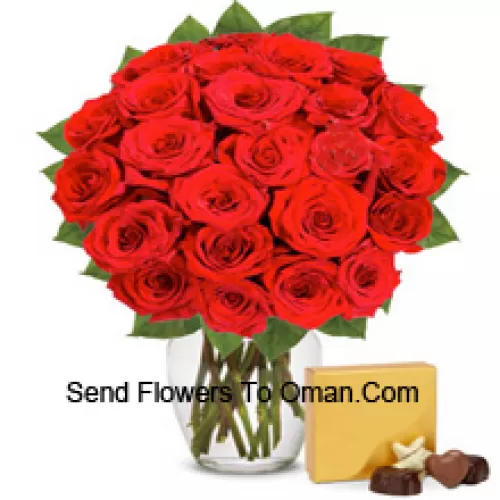 30 Punaiset ruusut muutamien saniaisten kera lasimaljakossa, mukana tuotu suklaarasia