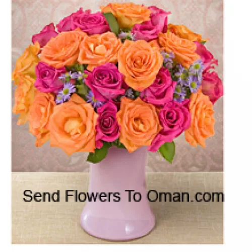 12粉色和12橙色玫瑰，配有季节性的填充物，放在玻璃花瓶中