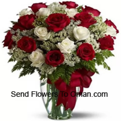 12 punaista ja 12 valkoista ruusua muutamien saniaisten kanssa lasimaljakossa