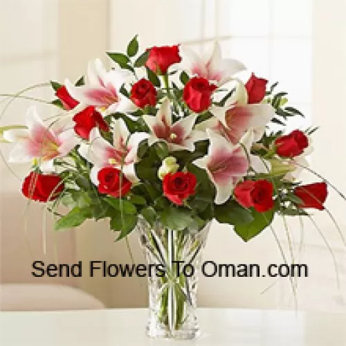 ガラスの花瓶に赤いバラとピンクのユリ、季節の花で飾られたアレンジメントです。
