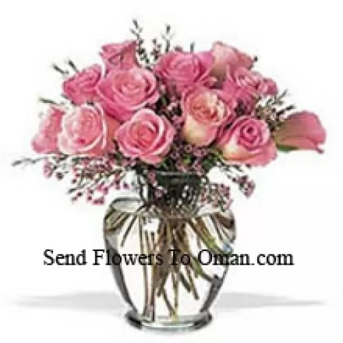 Un buchet de 12 trandafiri roz cu câteva frunze de ferigă într-o vază