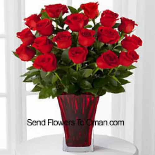 18朵红玫瑰搭配季节性花材，装在玻璃花瓶中，并用粉红色蝴蝶结装饰